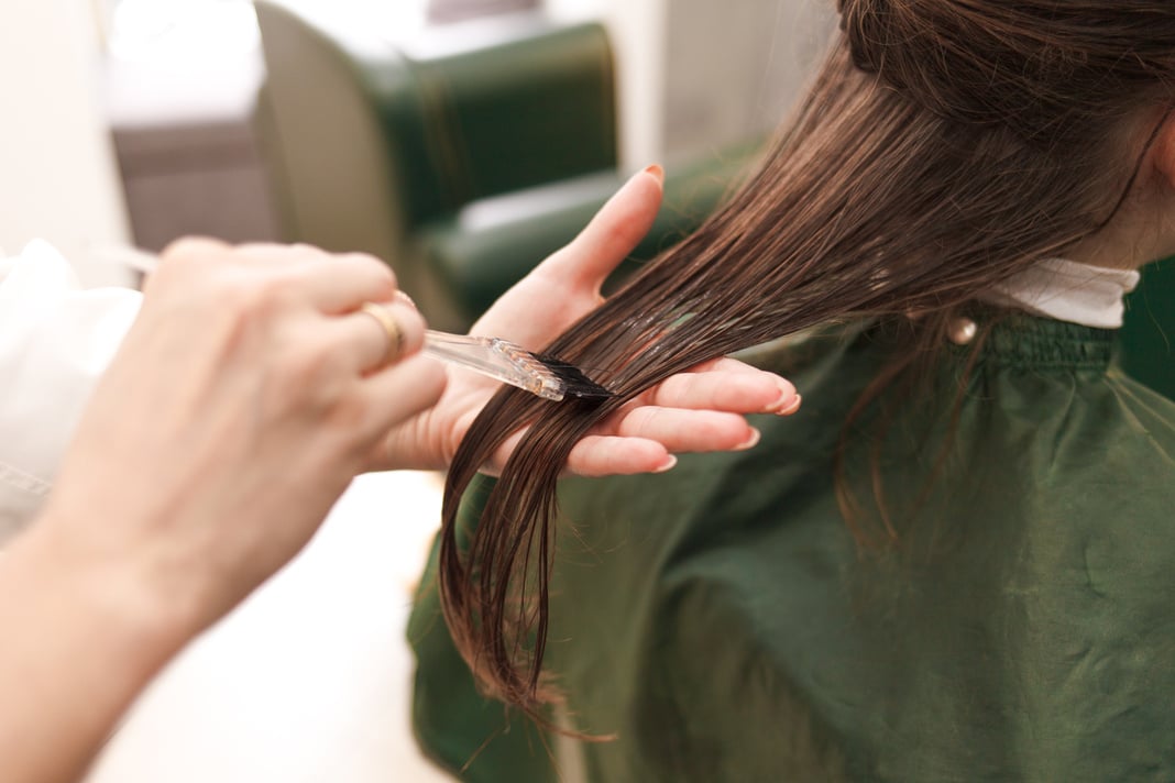 Hairdresser applies a hair mask to the woman in the beauty salon. Botox and keratin hair straightening procedure